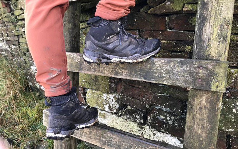 climbing up a slippy stile in the adidas terrex Skychaser