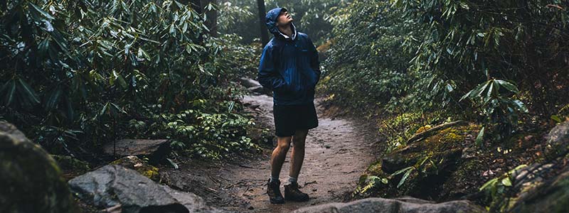 man standing in rain wearing patagonia waterproof jacket