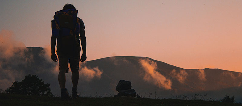 person on a backpacking adventure at sunset