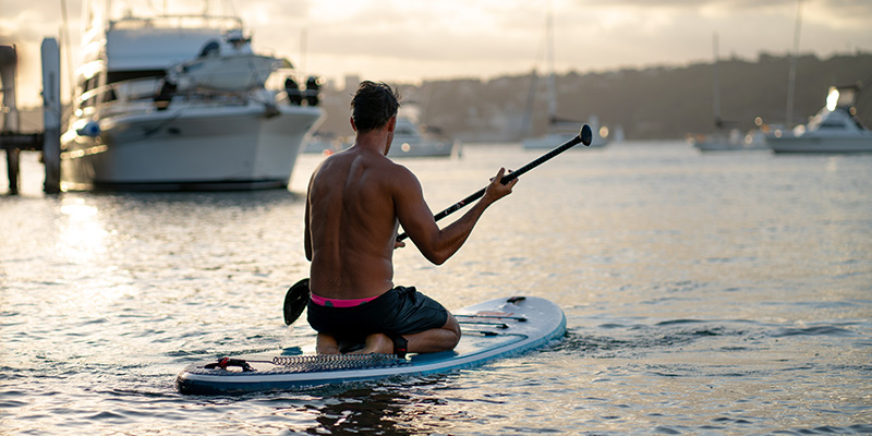 A man kneeling on his SUP