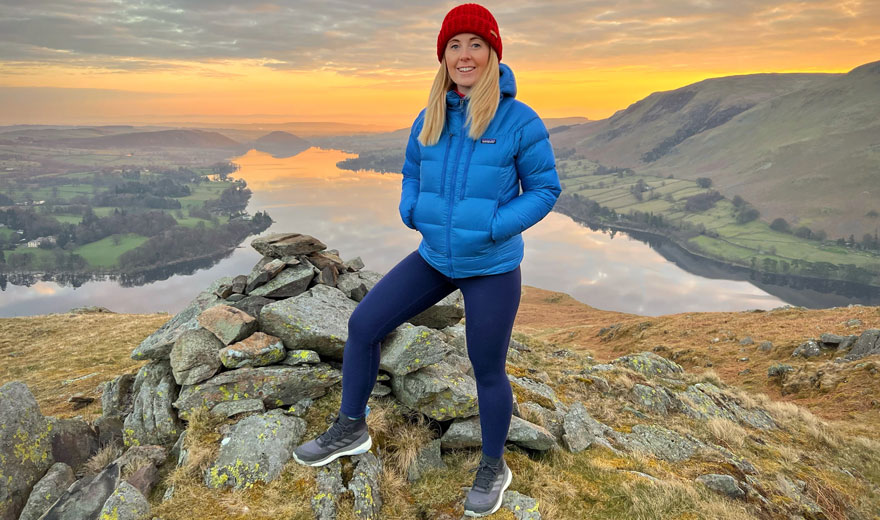Laura Jones standing on top of a hill with a gorgeous sunrise behind her