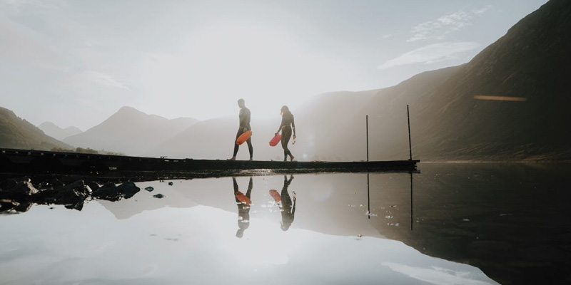man and woman walking wearing wetsuits