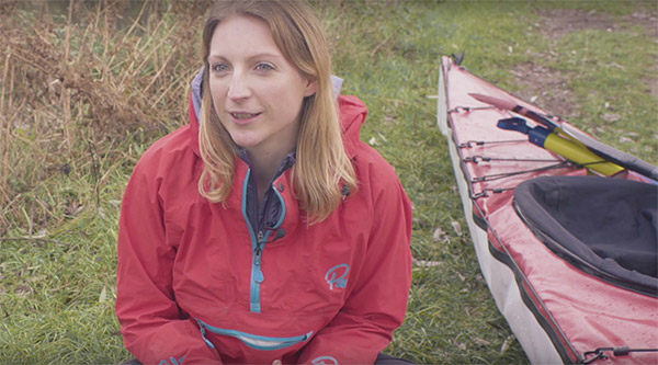 Laura Kennington sitting in front of a kayak