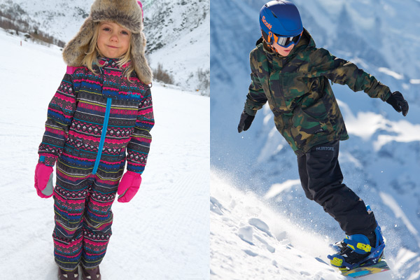young girl wearing snowsuit and young boy snowboarding