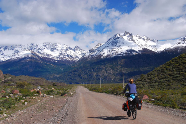 A woman riding a bike toward mountains