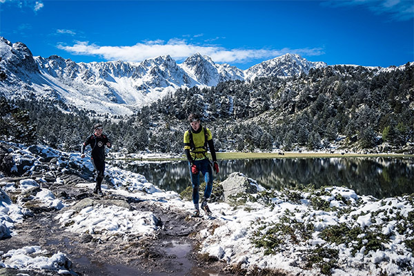 two male runners in fornt of a lake and mountains in winter